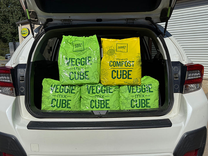 Packages labeled 'Veggie Mix Cube' and 'Compost Cube' in the trunk of a car.