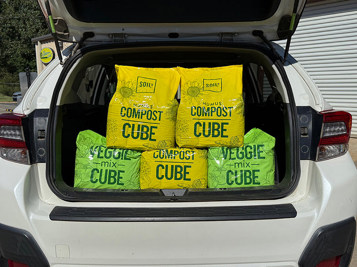 Compost and veggie mix cubes in a car trunk with visible branding.